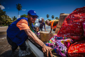 IOM staff pushing a boat full of emergency NFI’s in order to reach flood affected villages located in jungle areas of Popondetta, Papua New Guinea. ©Muse Mohammed